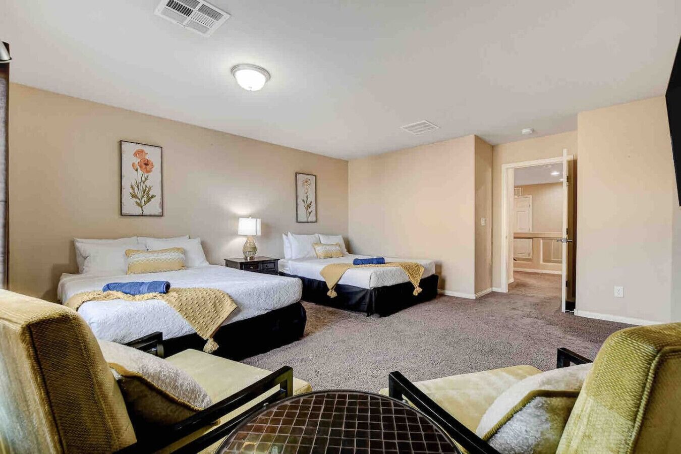 Een hotelkamer met twee bedden, een bureau, een stoel en een deur naar de badkamer.