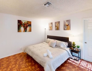 Een slaapkamer met een bed, een bedlamp en wanddecoratie.
