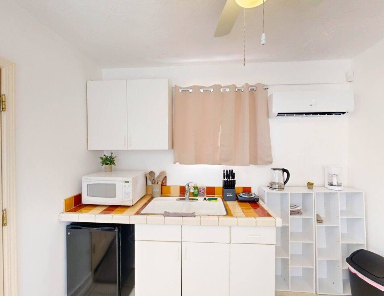 Een kleine keuken met een magnetron, spoelbak en koffiezetapparaat.