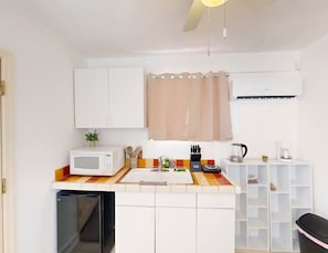 Een kleine keuken met een magnetron, spoelbak en koffiezetapparaat.