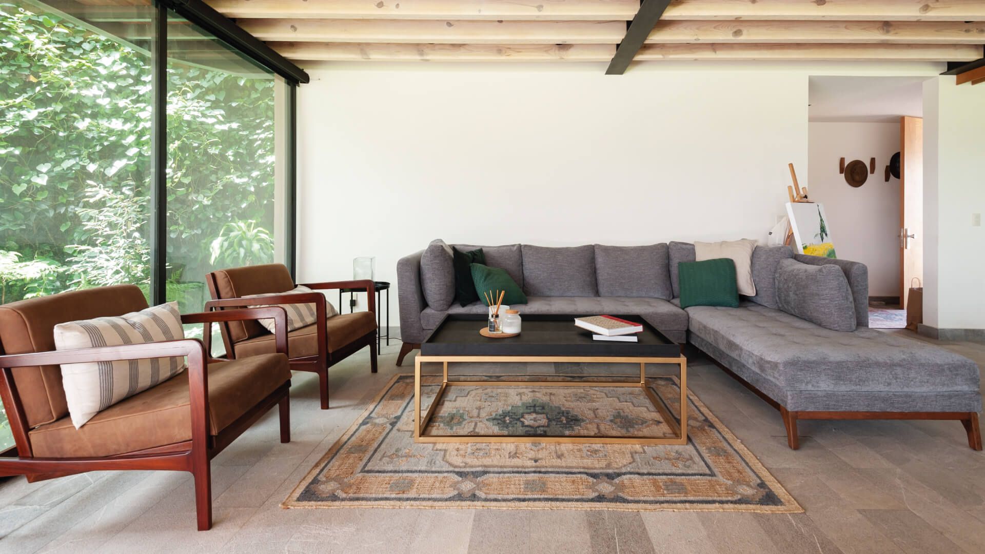 A modern living room with a grey sectional sofa, a brown leather armchair, and a wooden coffee table.