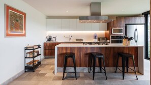 A modern kitchen with a large island, bar stools, and a coffee machine. - Casa Gala: With spectacular valley view (Valle de Bravo)