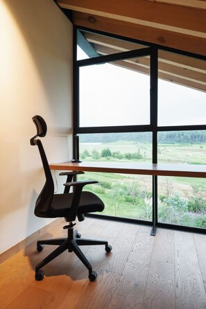 A modern office chair with a high backrest and armrests, positioned next to a large window with a view of a green landscape. - Casa Gala: With spectacular valley view (Valle de Bravo)