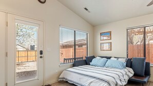 Un dormitorio con una cama, una puerta y dos ventanas.