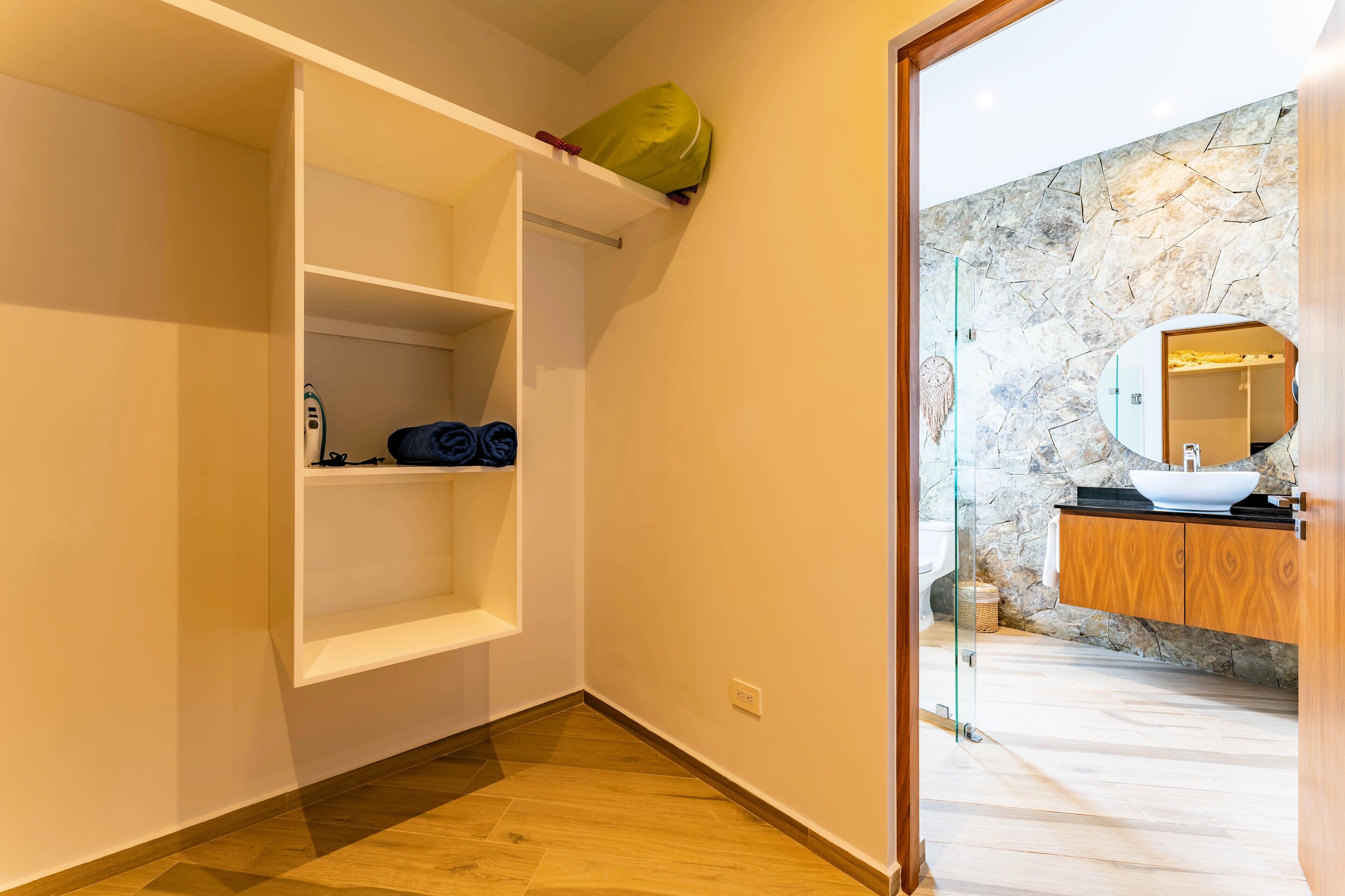 A modern bathroom with a stone wall, a wooden vanity, and a glass shower enclosure.