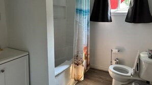 Un baño con bañera, inodoro y cortina de ducha.