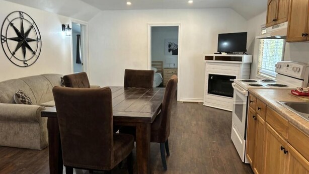 Un espacio habitable compacto con zona de comedor, kitchenette y un gran reloj de pared.