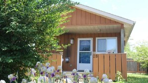 A wooden house with a porch, number 28, surrounded by iris flowers. - Jacuzzi Cabin - 25 min to Blue Mountain,  3 min Walk to Beach (Wasaga Beach)