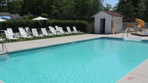 A rectangular swimming pool with clear blue water, surrounded by white lounge chairs and a small shed. - Jacuzzi Cabin - 25 min to Blue Mountain,  3 min Walk to Beach (Wasaga Beach)