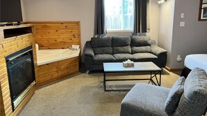 A cozy living room with a fireplace, a sofa, a coffee table, and a window with curtains. - Jacuzzi Cabin - 25 min to Blue Mountain,  3 min Walk to Beach (Wasaga Beach)