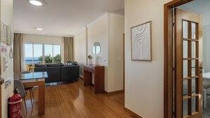 Ampla sala de estar com sofá, mesa de jantar e piso de madeira.