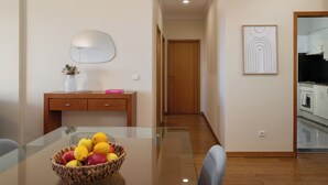Uma cozinha moderna com uma mesa de jantar de vidro, um armário de madeira e uma fruteira.