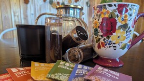 A table with a coffee maker, a mug, and tea packets. - Owl's Nest at Feather Nest Inn (Grand Marais)