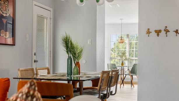 A dining area with a glass table, chairs, and a plant centerpiece. - Playtime Bonanza House - Game Room & Playground (Austin)