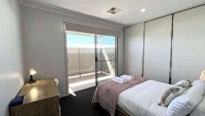 Une chambre d’hôtel moderne avec un lit, une table de chevet et une vue sur un balcon.