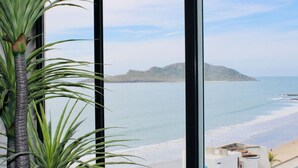 A view from a window overlooking a beach with a mountain in the distance. - The O apartments (Mazatlán)