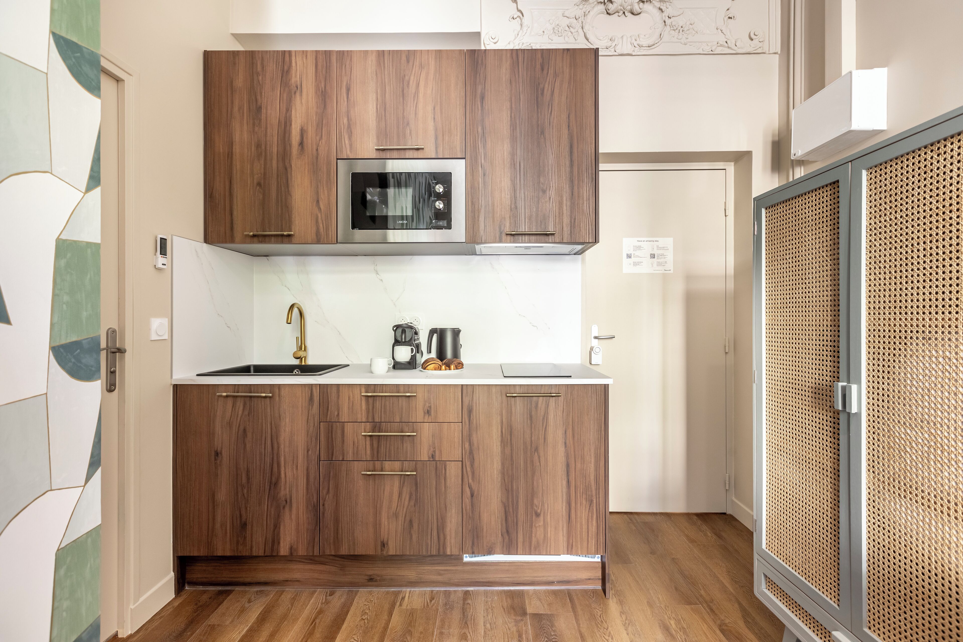 Une cuisine moderne avec des meubles en bois, un four à micro-ondes encastré et une machine à café.