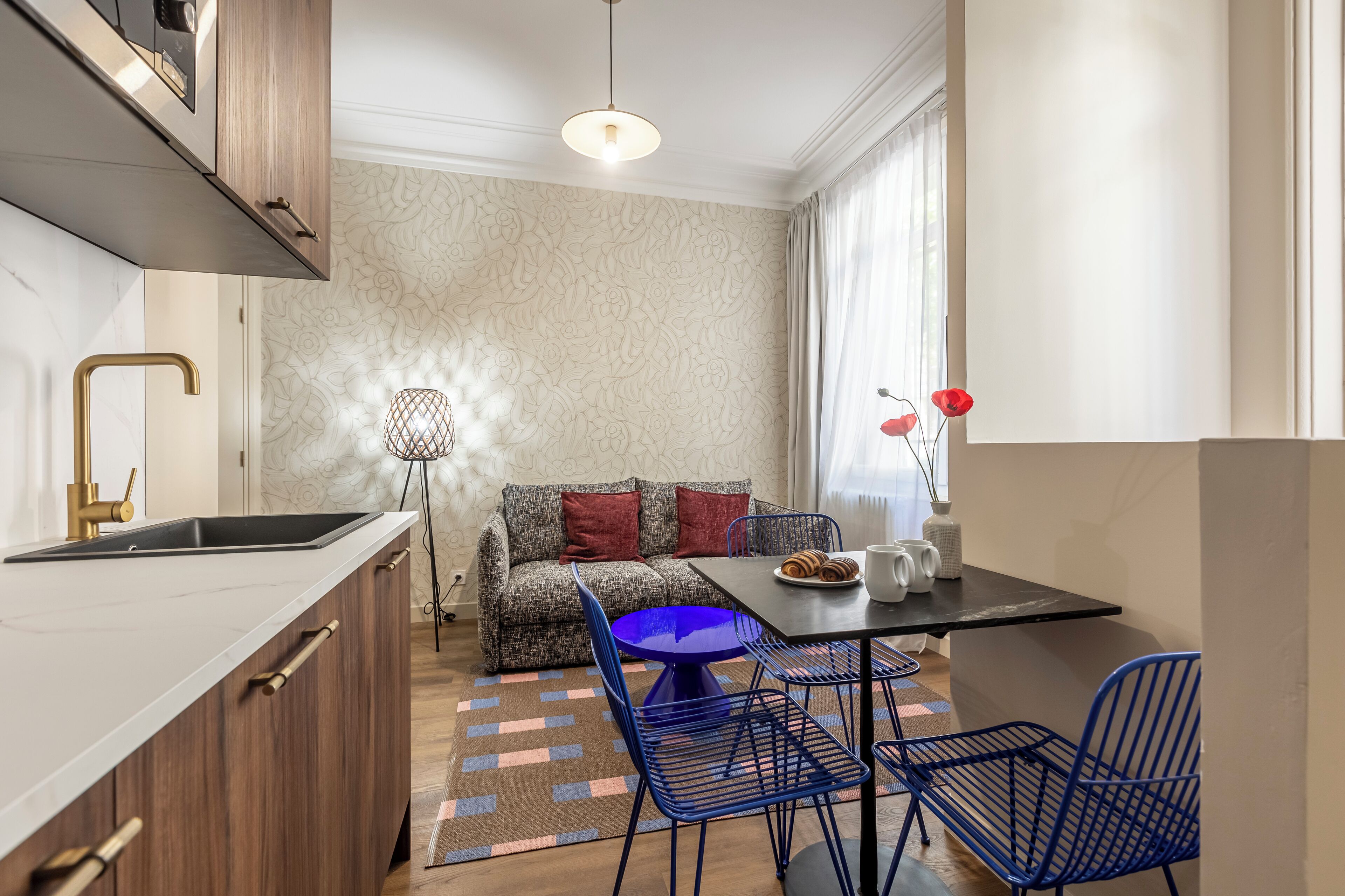 Une cuisine compacte comprenant un évier, un coin repas avec une table et des chaises, un canapé et une lampe de sol décorative.