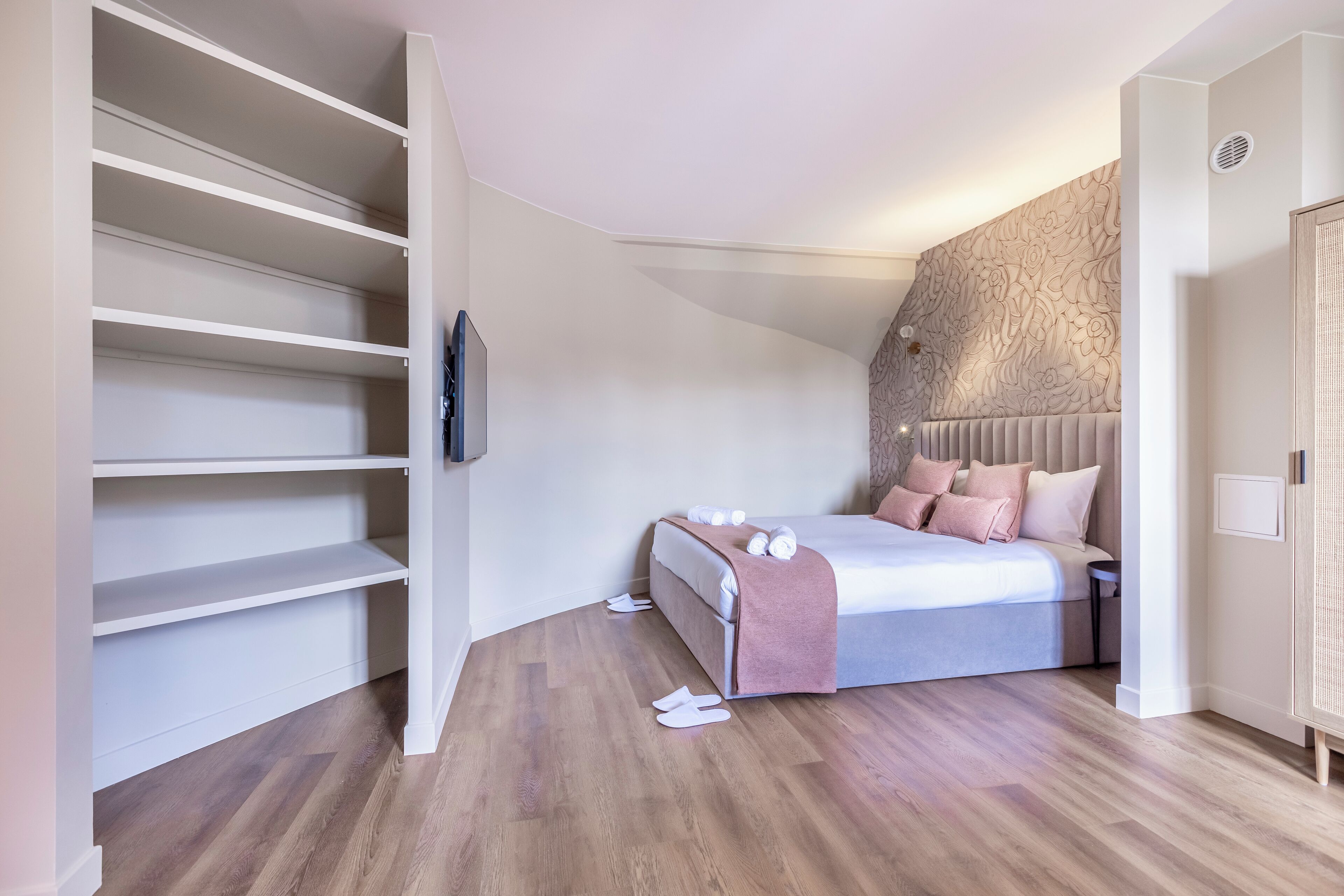 A bedroom with a bed, a wardrobe, and a built-in shelf unit.