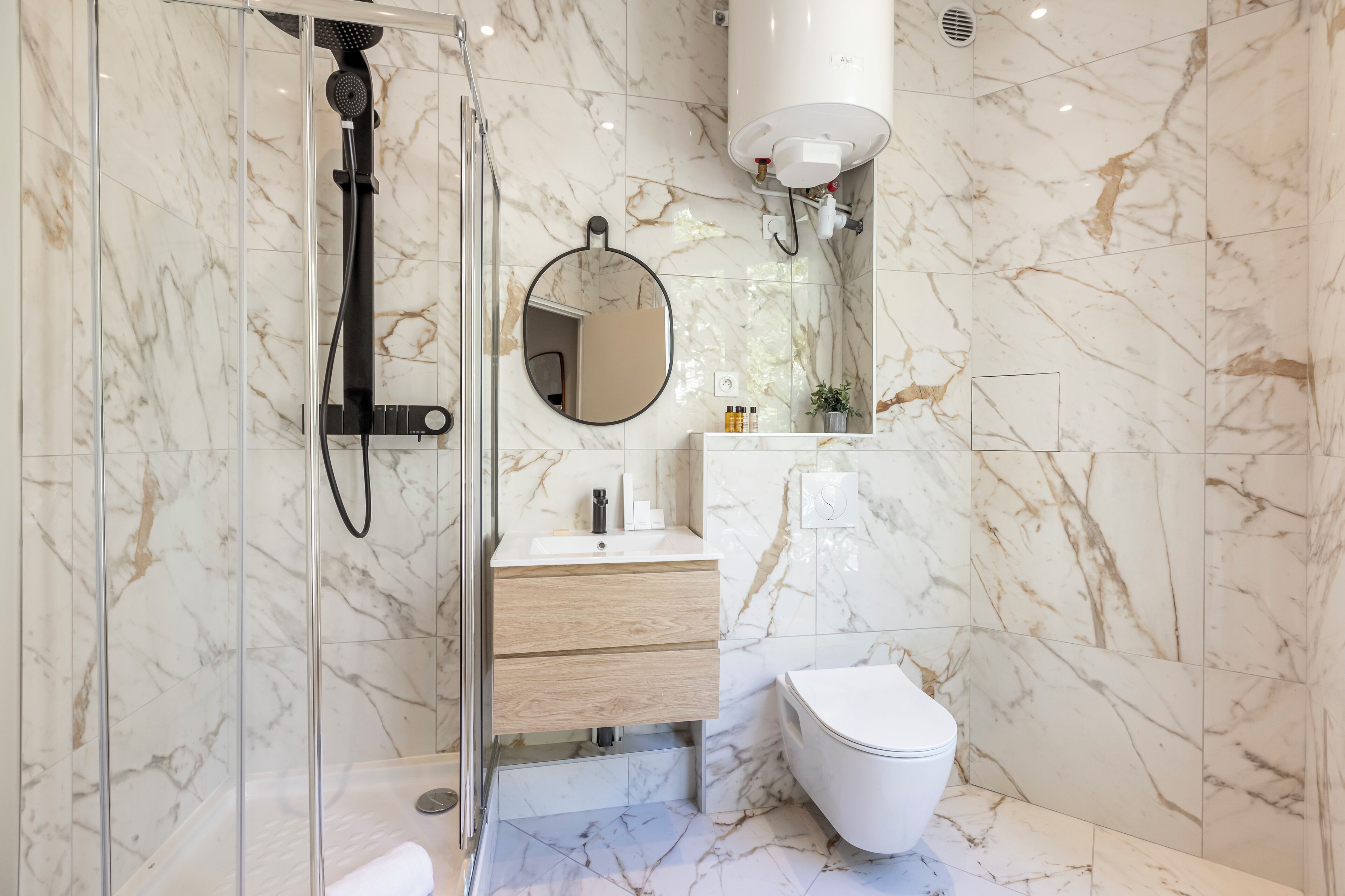 Un baño moderno con ducha envuelta en vidrio, tocador de madera con espejo y un inodoro.