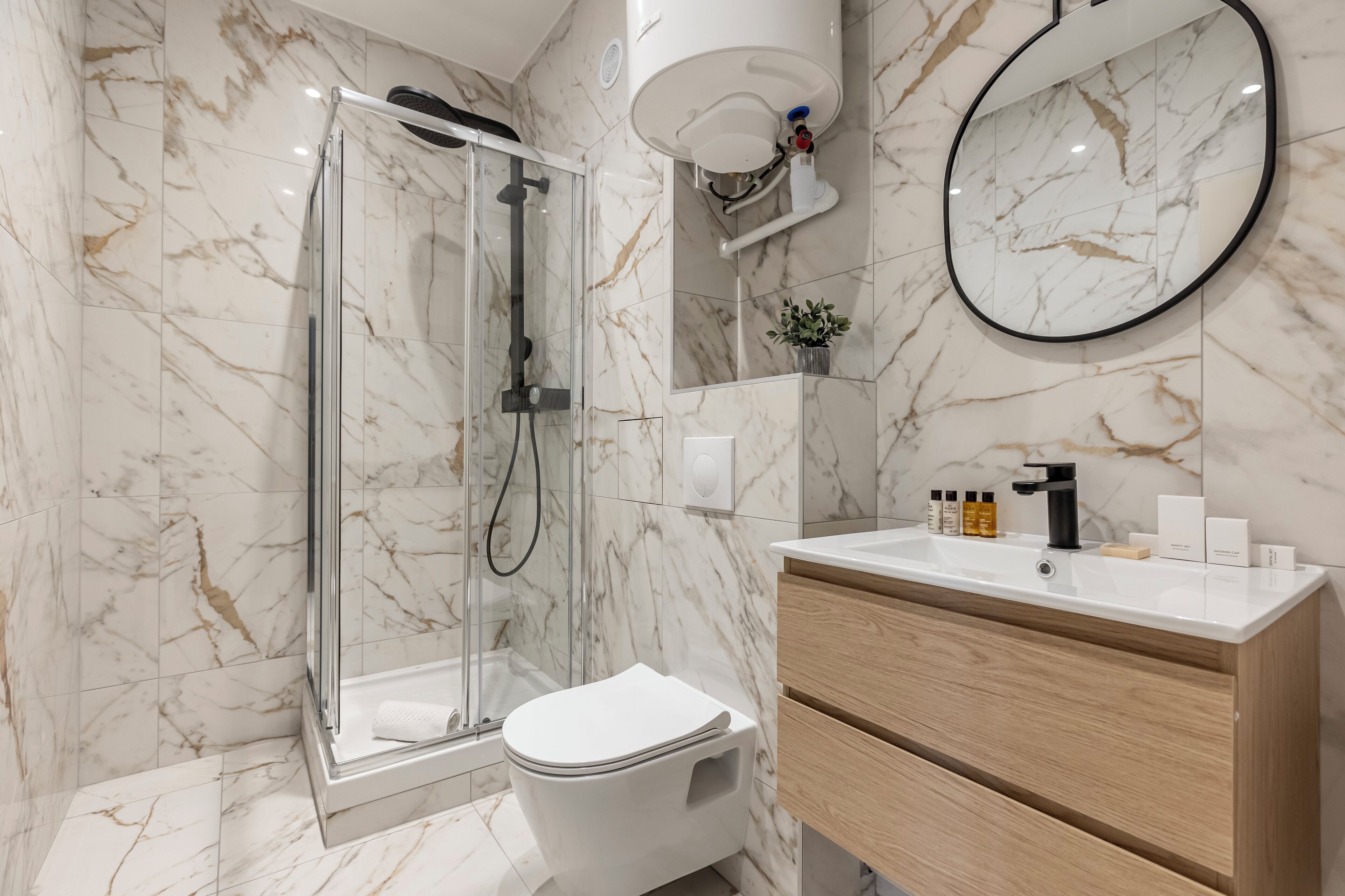 A modern bathroom with a glass-enclosed shower, a white toilet, and a wooden vanity with a sink.