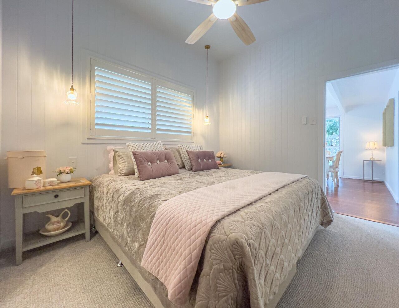 A bedroom with a bed, bedside tables, a ceiling fan, and a window with blinds.