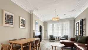 Ett rymligt vardagsrum med ett matbord i trä, en brun lädersoffa och ett runt soffbord.