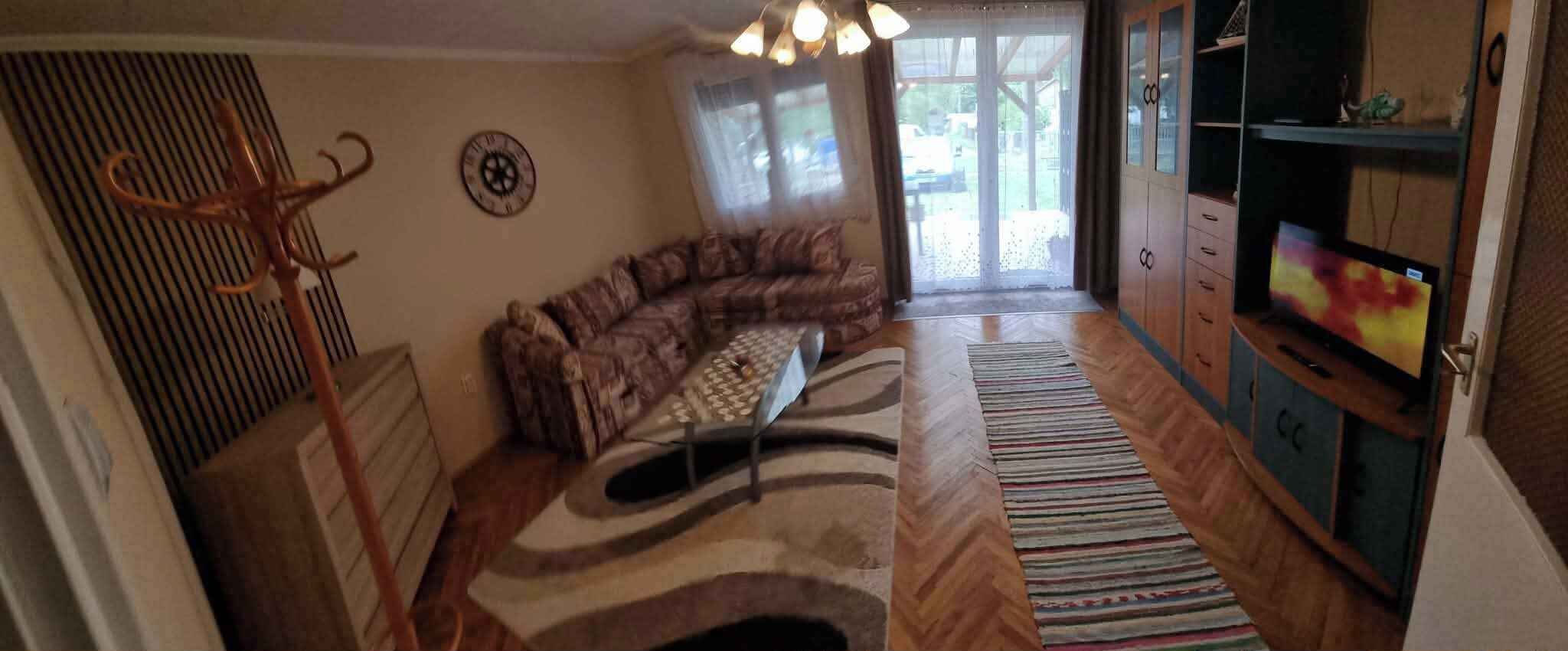 Un soggiorno con un divano, un tappeto decorato, un televisore e un mobile in legno.