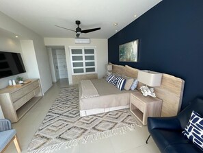 A modern bedroom with a bed, bedside tables, a TV, and a ceiling fan. - Marival Luxury 4BR-4BTh Ocean View Condo w/ Rooftop & Private Pool & BBQ Area (Nuevo Vallarta)