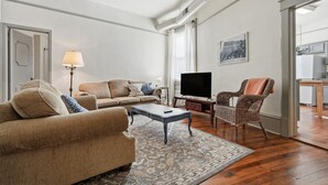 Ein Wohnzimmer mit Sofa, Couchtisch, Fernseher und einem Korbstuhl.