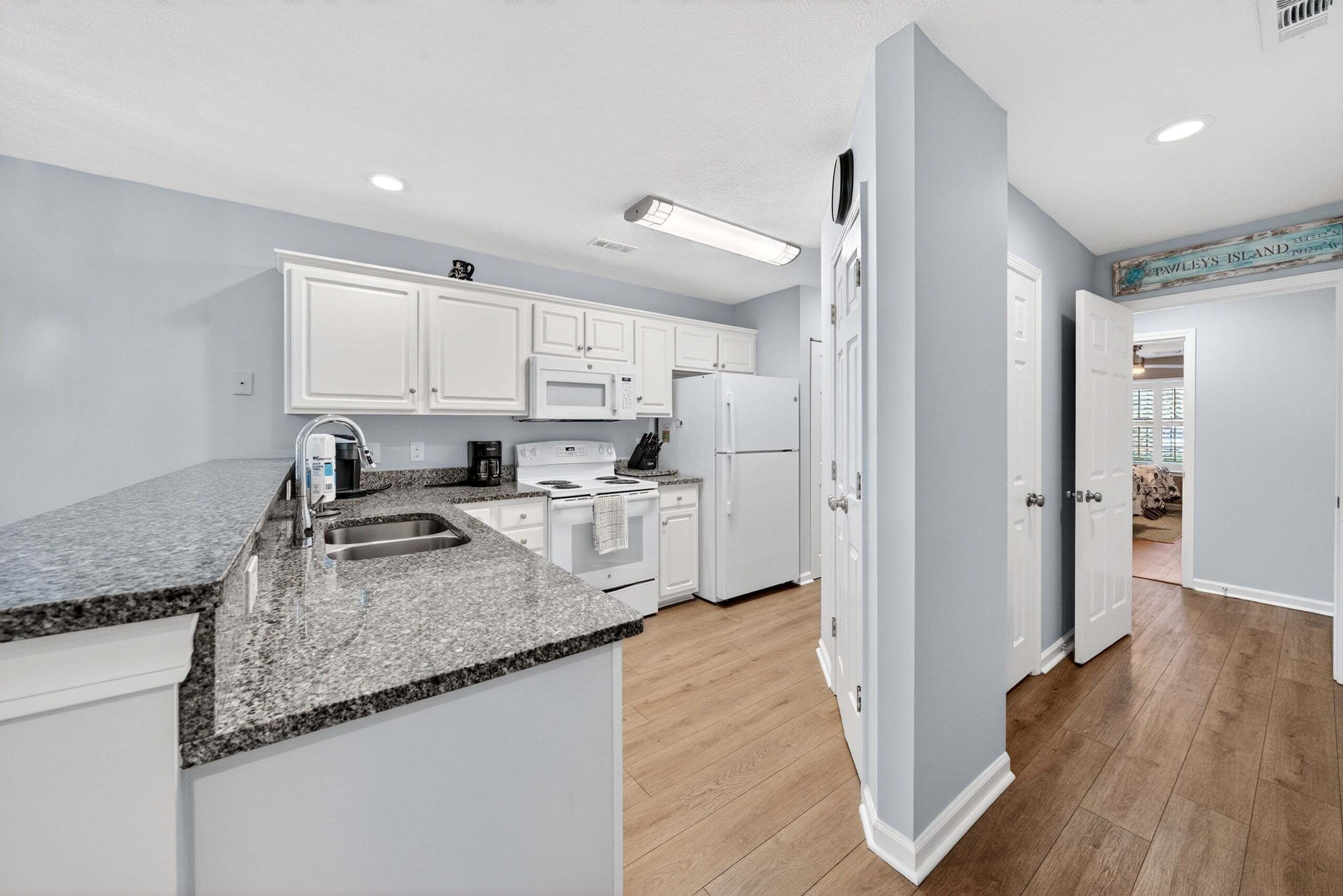 A modern kitchen with white cabinets, granite countertops, and a built-in microwave.