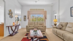 Un salon avec un canapé beige, une table basse et un coin repas comprenant une table et des chaises.