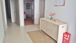 Ein Flur mit einem hellen Holzschrank, einer Pinwand und einem roten Mülleimer.