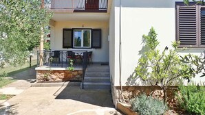 Ein zweistöckiges Gebäude mit einem Balkon, einem Tisch mit Stühlen und einem kleinen Garten.