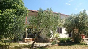 Ein zweistöckiges Haus mit rotem Ziegeldach, umgeben von Bäumen und einem eingezäunten Garten.