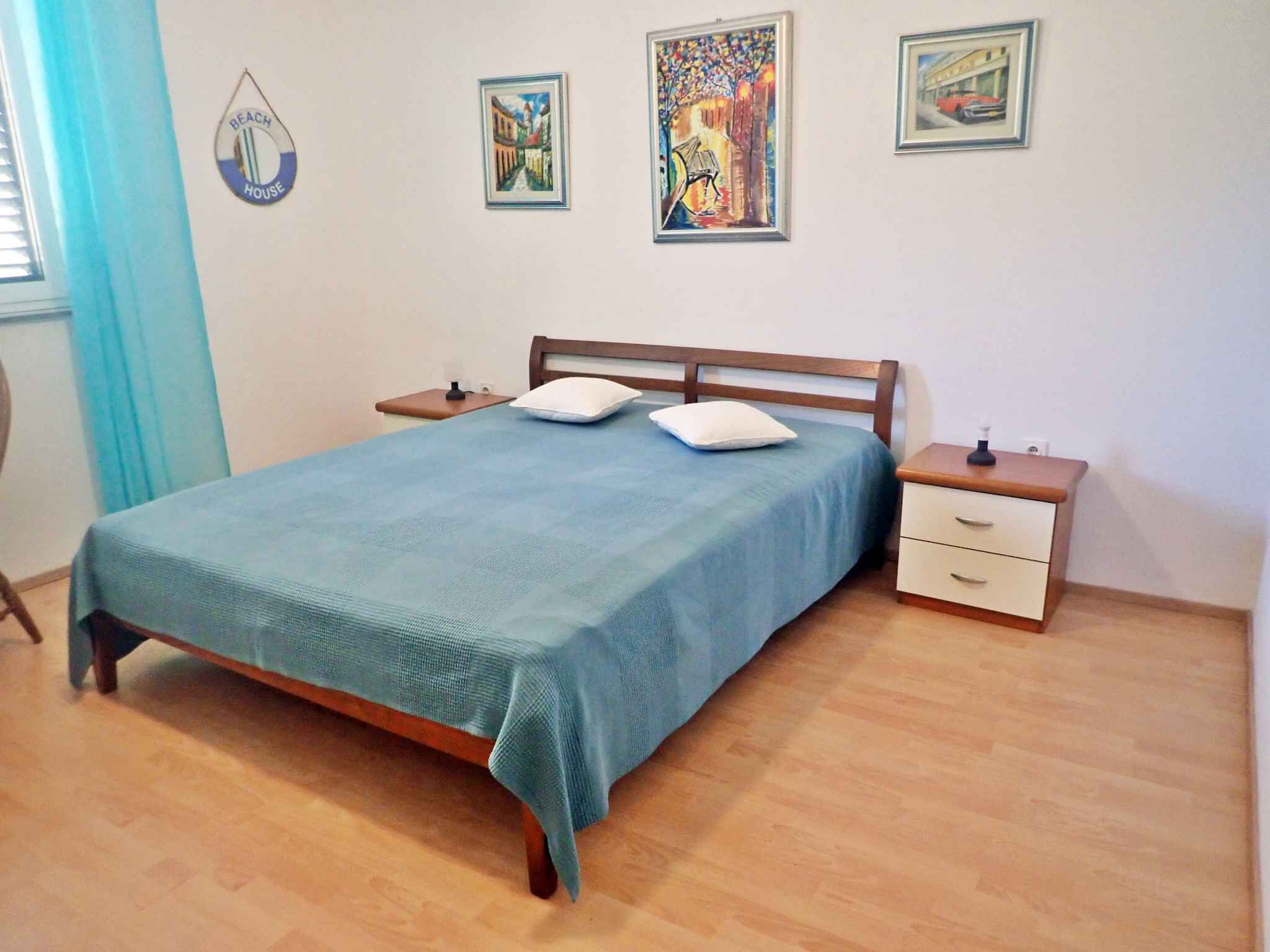 A bedroom with a bed, two bedside tables, and three framed artworks on the wall.