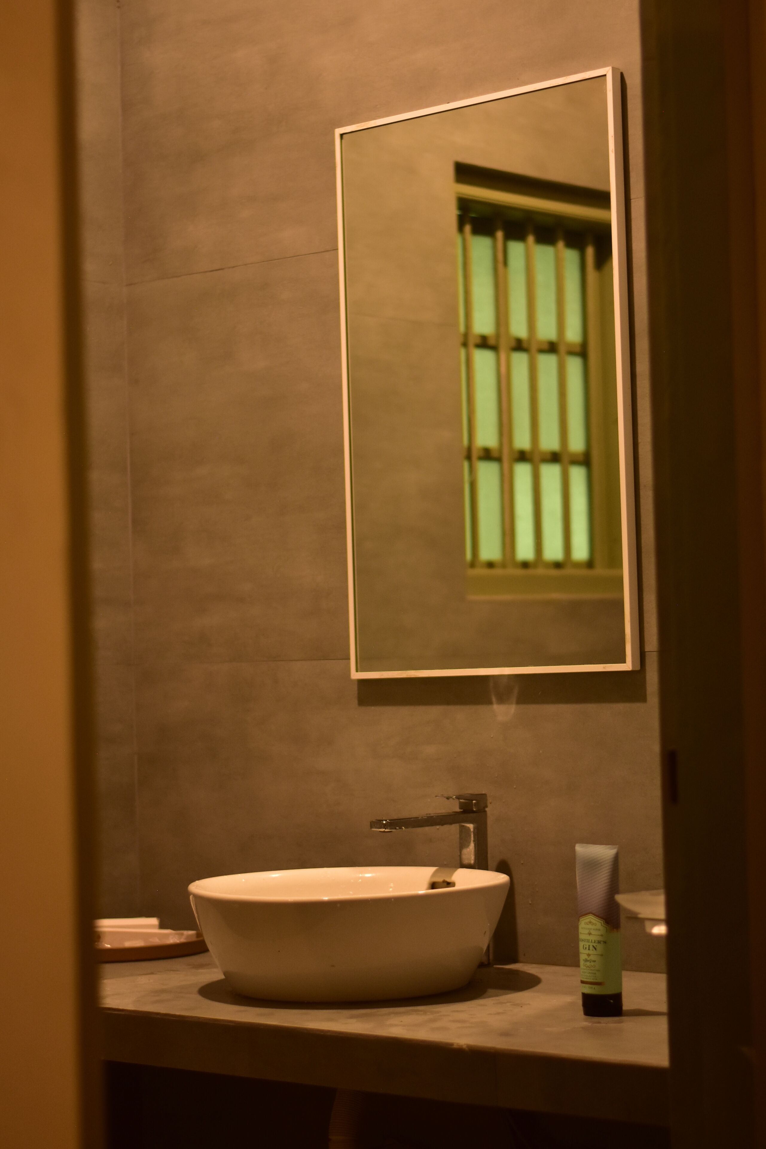Un baño con lavamanos blanco, un espejo y una botella de loción.