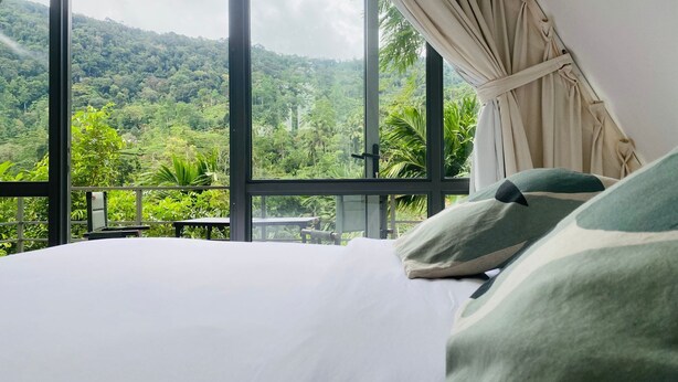 A bedroom with a large window overlooking a lush green landscape. - Rain Drops Wellness Villa Sinharaja (Mederipitiya)