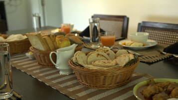 A dining table with bread, a bowl of soup, and a glass of juice.