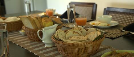 A dining table with bread, a bowl of soup, and a glass of juice.