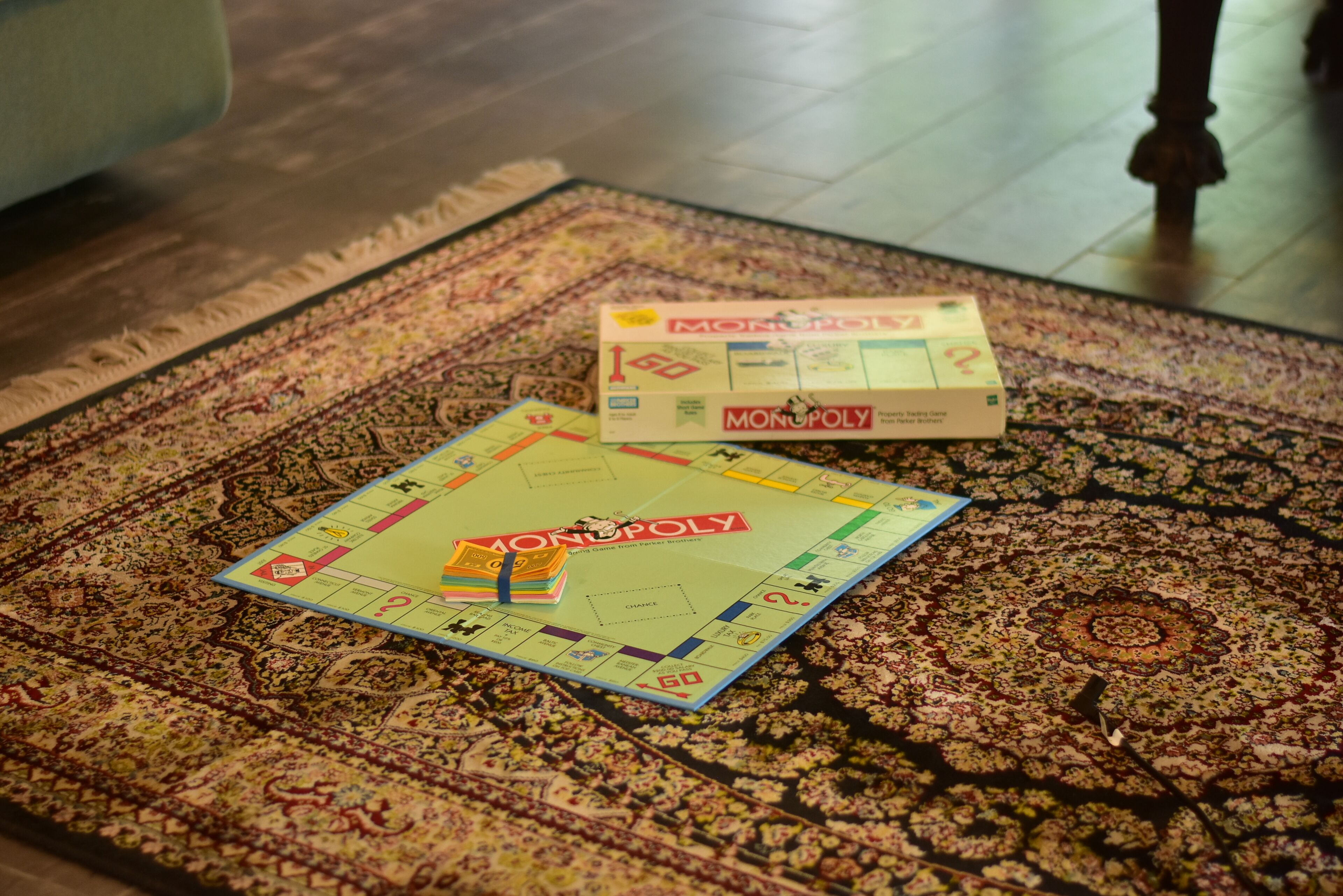 A Monopoly board game on a patterned rug.