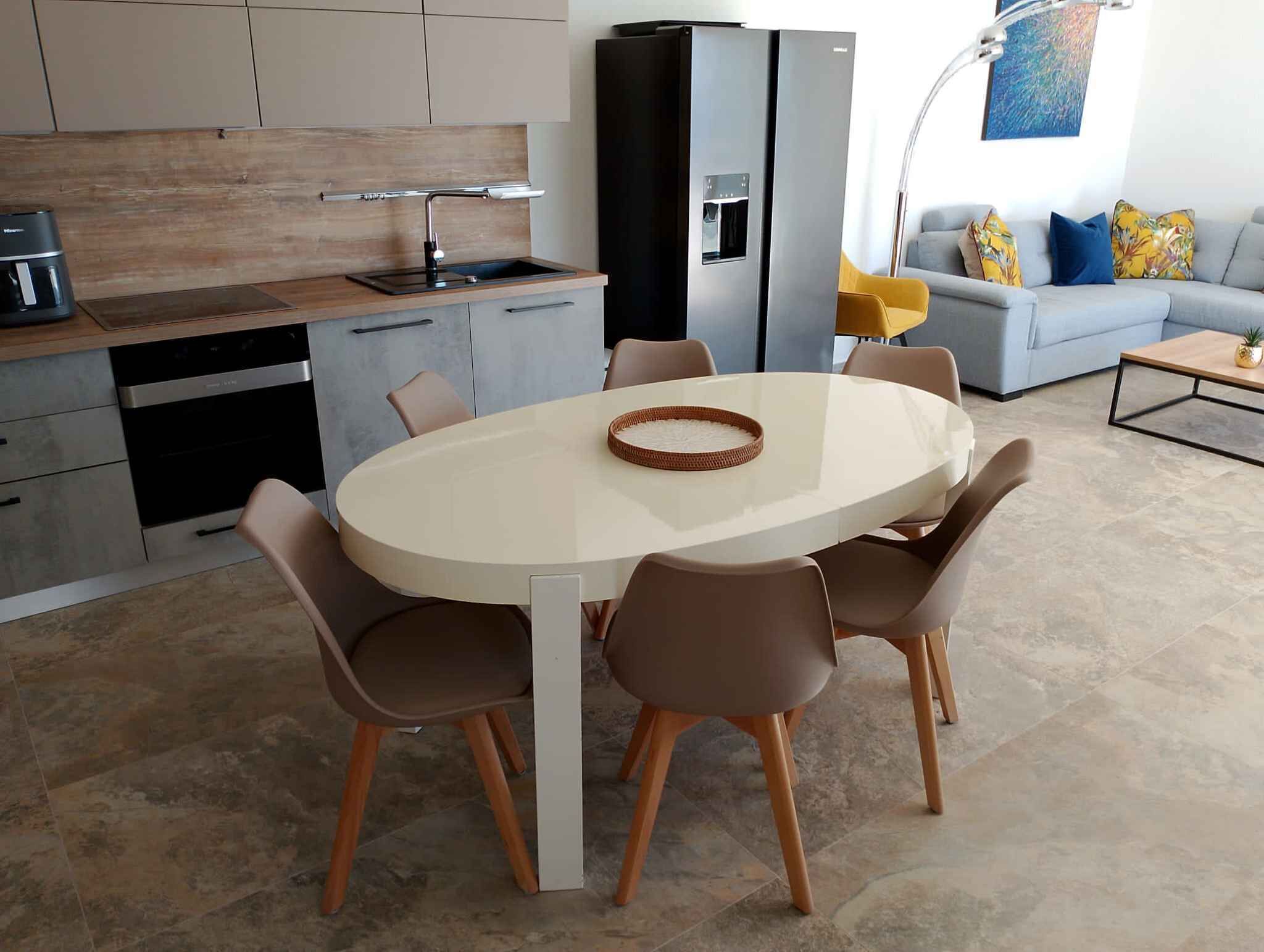 Una cocina moderna con una mesa de comedor redonda y sillas, un horno empotrado y un dispensador de agua.