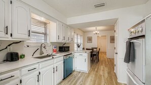 Uma cozinha moderna com armários brancos, lava-louças, micro-ondas e frigorífico.