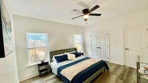 Un dormitorio con cama, mesitas de noche, ventilador de techo y ventana con persianas.
