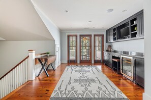 A modern kitchen with dark cabinetry, a built-in oven, and a large island. - Gem in Wilson Village with Private Pool, Game Room, and Bikes (Bluffton)