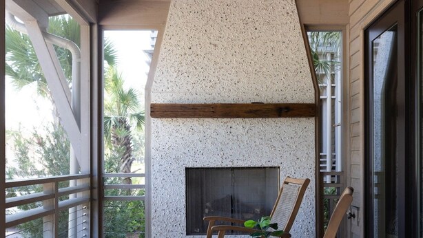 Un terrazzo in legno con camino, posti a sedere e una ventola a soffitto.