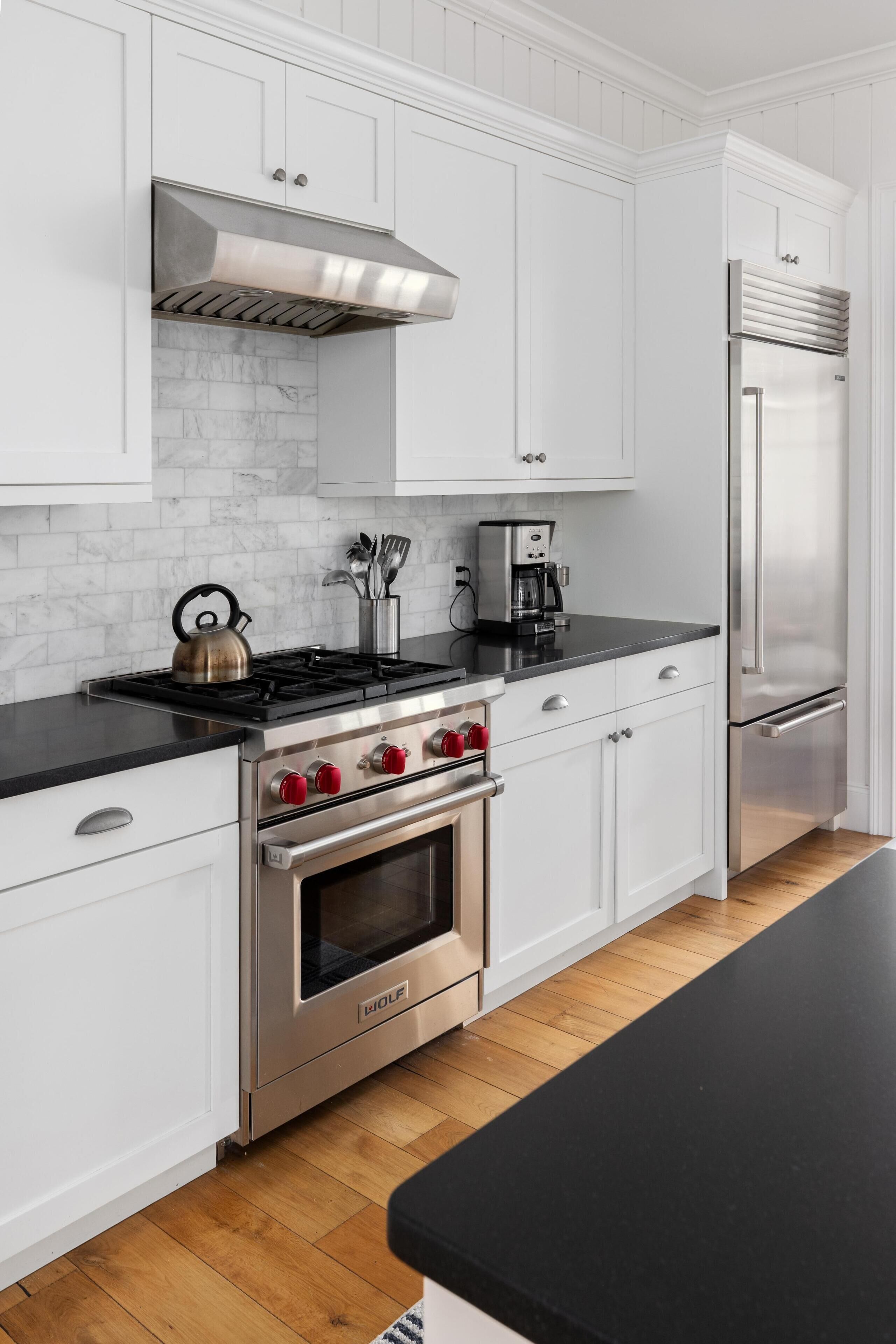 A modern kitchen with white cabinetry, a stainless steel stove, and a built-in oven.