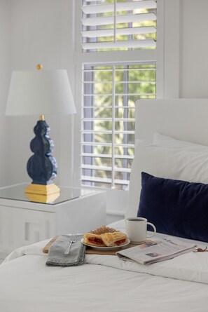 A neatly made bed with a pillow, a bedside table with a lamp, a plate with food, a cup, and a newspaper. - Newly Renovated! Now 5 Bedrooms & Firepit. Fall Bookings include Complimentary Bikes! (Bluffton)