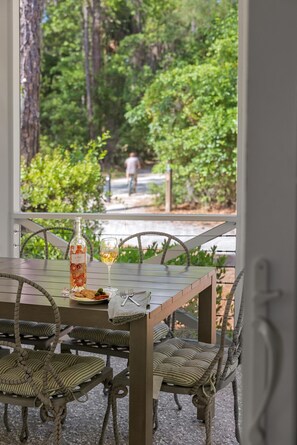 A dining table with wicker chairs, a bottle of wine, and a glass. - Newly Renovated! Now 5 Bedrooms & Firepit. Fall Bookings include Complimentary Bikes! (Bluffton)