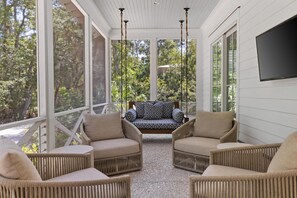 A covered outdoor seating area with wicker furniture and a view of the surrounding trees. - Newly Renovated! Now 5 Bedrooms & Firepit. Fall Bookings include Complimentary Bikes! (Bluffton)